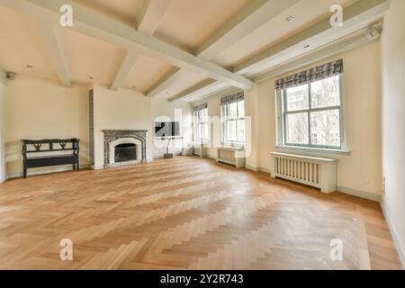 Elegantes und luftiges Wohnzimmer mit Holzfußboden mit Fischgrätenmuster, großen Fenstern und klassischem Kamin. Stockfoto