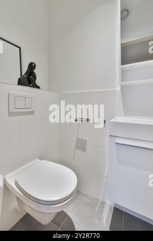 Ein modernes Badezimmer mit minimalistischem Design, weißen Schränken und einer künstlerischen schwarzen Skulptur. Stockfoto