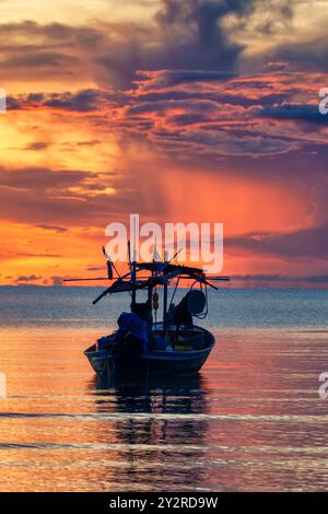 Farbenfroher Sonnenaufgangshimmel über dem traditionellen Fischerboot im tropischen Meer in Phetchaburi, Thailand Stockfoto
