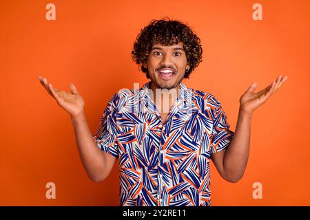 Foto-Porträt des netten jungen Mannes erstaunte Reaktion tragen trendiges buntes Outfit isoliert auf orangefarbenem Hintergrund Stockfoto