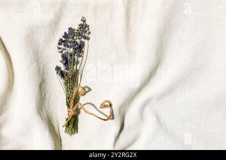 Zweige violetter Lavendelblüten auf Leinengewebe. Trockenblumenkomposition in Pastellfarben. Stockfoto