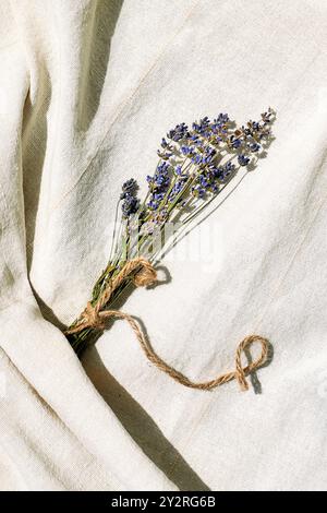 Zweige violetter Lavendelblüten auf Leinengewebe. Trockenblumenkomposition in Pastellfarben. Stockfoto