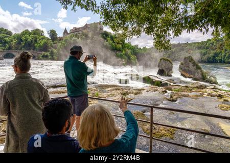 Rheinfall in Schaffhausen, Schweiz, Touristen schauen von einer Plattform auf den berühmten Wasserfall, Gemeinde Neuhausen am Rheinfall, September 2024 Schweiz, Neuhausen am Rheinfall, September 2024, Rheinfall in Schaffhausen, Touristen schauen von einer Plattform auf den berühmten Wasserfall, filme mit dem Handy, Wassermassen stürzt 23 Meter tief auf 150 Meter Beite, das grandiose Naturschauspiel gilt als der größte Wasserfall Europas, in Schweizerdeutsch heißt der Rheinfall Rhyfall, Tourismus, Touristenattraktion, Herbst, *** Rheinfälle in Schaffhausen, Schweiz, Touristen schauen von A Stockfoto