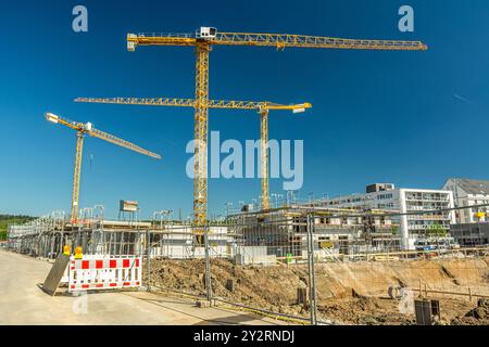 Große Baustelle mit Kränen, Zaunfundamenten und unfertigen Gebäuden Stockfoto