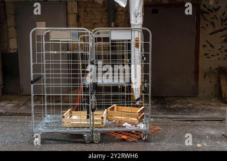 Zwei Metallwagen mit Holzkisten vor einem Gebäudeeingang Stockfoto