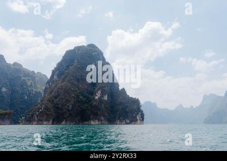 Eine ruhige Landschaft mit hoch aufragenden Felsformationen, umgeben von ruhigem Wasser, mit einem bewölkten Himmel, der eine friedliche Atmosphäre in Thailands na schafft Stockfoto