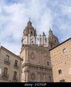 Blick auf die Kirche Clerecia und die Casa de las Conchas in Salamanca, Spanien, unter teilweise bewölktem Himmel Stockfoto