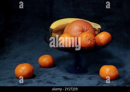 Die niedrige Taste zeigt eine Obstschale gefüllt mit Mandarinen, Bananen und Grapefruit. Stockfoto