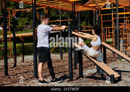 Eine junge Frau und ein tätowierter Mann mit Beinprothetik trainieren nebeneinander und zeigen Kraft und Freundschaft im Park. Stockfoto