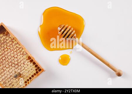 Löffel mit verschüttetem Honig und Bienenwabe auf weißem Hintergrund, Blick von oben, Imkerei-Konzept Stockfoto