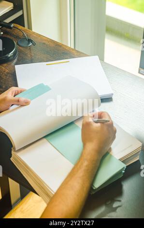 Mann, der im Heimbüro auf Notizbuch schreibt. Die Aussicht von oben. Hochwertige Fotos Stockfoto