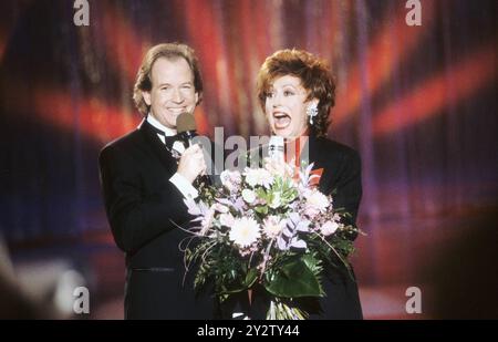 FOTOREPERTOIRE - Max Schautzer mit Caterina Valente 01/91 - Max Schautzer mit Caterina Valente im Januar 1991 im ARD-Wunschkonzert Frau Mann Moderation TV Fernsehen Moderatorin Moderatoren S''°ngerin Schauspielerin T''°nzerin Moderatorin Sängerin Tänzerin Schauspielerin quer halb stehend lÂ €°chelnd lachend Blumen (keine - 1991-01-01, imago Stock&People via www.imago-images.de/ipa-agency.net) ps das Foto kann in Übereinstimmung mit dem Kontext verwendet werden, in dem es nur in welchem Verleumgangsabsichtlich wurde, ohne Verleumgangswillig Stockfoto