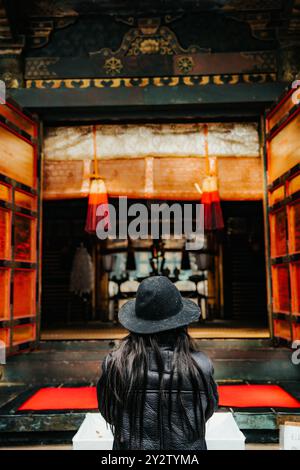 Ein Worshiper in Okumiya Haiden (Gotteshaus) auf dem Hügel im buddhistischen Shinto Toshogu Tempelkomplex in Niko Japan. Stockfoto