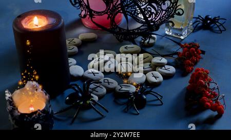 Runen auf dem Tisch, Kerzen, Spinnen, schwarze Maske, vogelbeeren. Stockfoto