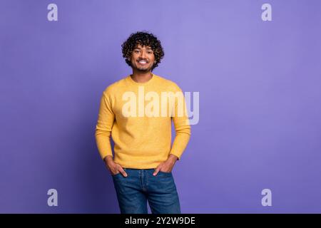 Foto des positiven netten Mannes tragen trendiges gelbes Sweatshirt isoliert auf violettem Hintergrund Stockfoto