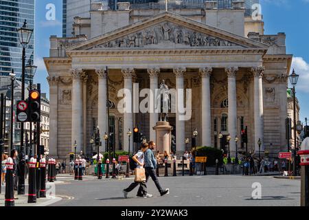 Zwei Leute überqueren die Straße vor der Royal Exchange an der Bank Junction in der City of London, London, Großbritannien Stockfoto