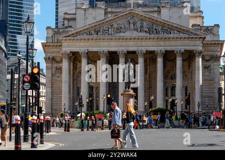 Zwei Leute überqueren die Straße an der Bank Junction vor der Westfassade der Royal Exchange, City of London, London, UK Stockfoto