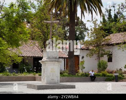 Ein Denkmal mit Einem Holzkreuz ziert den Parkplatz vor der Kirche Los Dominicos in Santiago de Chile Stockfoto