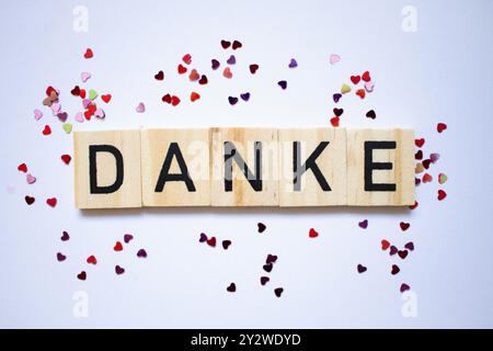 Dankeskarte in deutscher Sprache, Dankestext, kleine kleine, glänzende Herzen um Scrablle Buchstaben herum Stockfoto