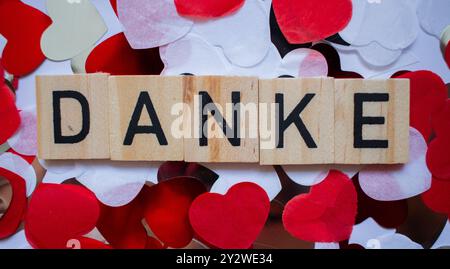 Dankeskarte in deutscher Sprache mit Wort DANKE auf Scrabble-Blöcken und Hintergrund aus Herzen Stockfoto