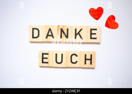 Dankeskarte in deutscher Sprache, einfaches Design mit zwei Herzen auf weißem Hintergrund und Scrabble-Buchstaben Stockfoto