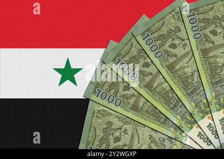 Syrische Flagge mit einem Fan von 1000 syrischen Pfund-Banknoten im Vordergrund. Stockfoto