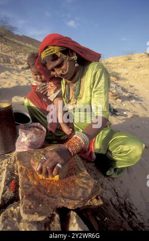 Eine Rajasthani-Frau hackt mit ihrem Baby in der Stadt Jaisalmer in der Provinz Rajasthan in Indien an einem Feuer. Indien, Jaisalmer, Januar 1998 Stockfoto