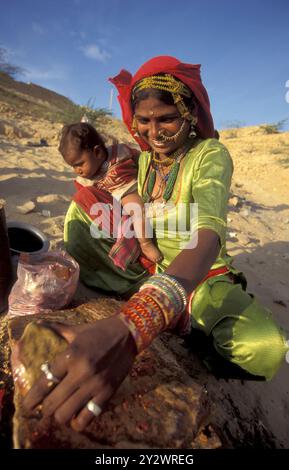 Eine Rajasthani-Frau hackt mit ihrem Baby in der Stadt Jaisalmer in der Provinz Rajasthan in Indien an einem Feuer. Indien, Jaisalmer, Januar 1998 Stockfoto