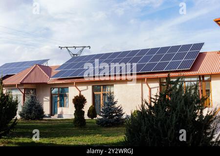 Ein Haus mit Solarpaneelen an einem klaren sonnigen Tag, mit teilweise bewölktem blauen Himmel im Hintergrund Stockfoto