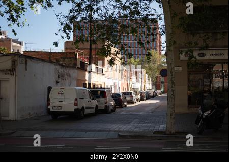 Detail einer Gasse im alten Arbeiterviertel Poble Nou in Barcelona. Niedrige Häuser und Arbeitsfahrzeuge parken entlang Stockfoto