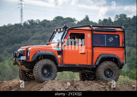 Seitenansicht eines schönen orangen Land Rover Defender, der für extreme Geländefahrten auf dem Land stark modifiziert wurde Stockfoto