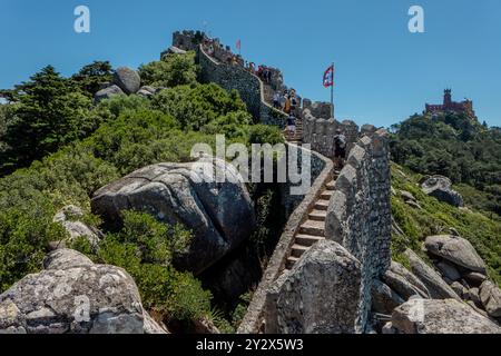 Die maurische Burg (Castelo dos Mouros) in Sintra wurde zuerst von den arabischen Eroberern der Iberischen Halbinsel erbaut, daher auch ihr Name, und später von den christlichen Herrschern Portugals genutzt. Das mittelalterliche Schloss befindet sich in strategisch günstiger Lage auf einem steilen Bergrücken mit Blick auf die Atlantikküste und die Ebenen nördlich von Lissabon und ist heute Teil des UNESCO-Weltkulturerbes der Parks von Sintra und eine beliebte Touristenattraktion. Im Hintergrund der Palácio da Pena, ein romantischer Palast, der im 19. Jahrhundert unter dem Befehl von König Ferdinand II. Erbaut wurde. Stockfoto