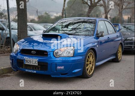 Vorderansicht eines schönen blauen Subaru Impreza STI der zweiten Generation mit goldenen Rädern, die auf der Straße geparkt sind Stockfoto