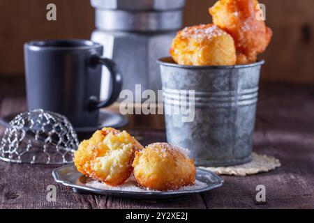 Quark Donuts mit Zucker serviert mit Tee oder Kaffee auf hellem Holzhintergrund. Rustikaler Stil. Stockfoto