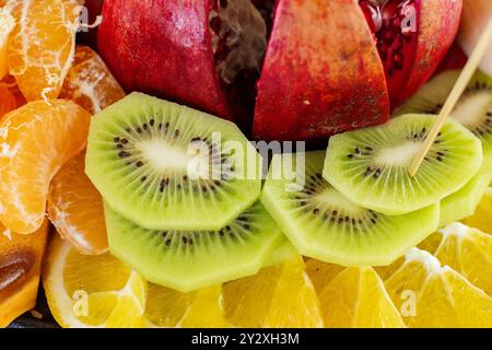 Eine Nahaufnahme von angeordneten Scheiben von Früchten einschließlich Granatapfel, Mandarine, Orange und Kiwi Stockfoto