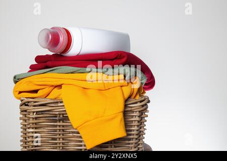 Stapel bunter gefalteter Kleidung in einem Korb mit einer Waschmittelflasche oben, bereit für den Wäschetag Stockfoto