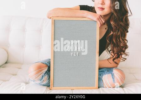 Eine Frau, die ein Schild hochhält, auf dem steht: „Ist es Freitag noch?“ Stockfoto