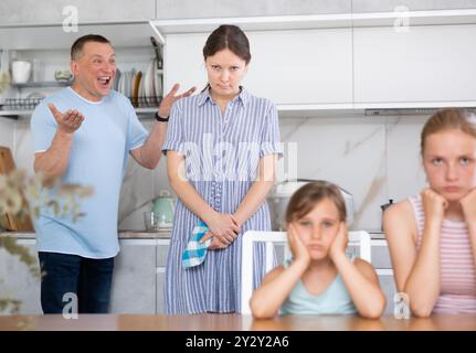 Der Ehemann schreit die Frau an, während die Kinder ihre Hände über die Ohren legen Stockfoto