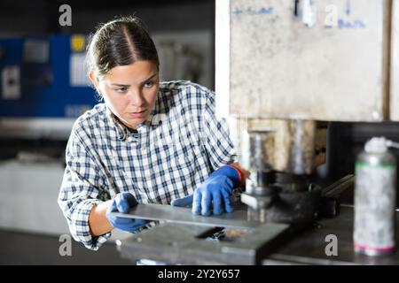 Junge Arbeitnehmerin in der Stanzpresse in der Metallwerkstatt Stockfoto