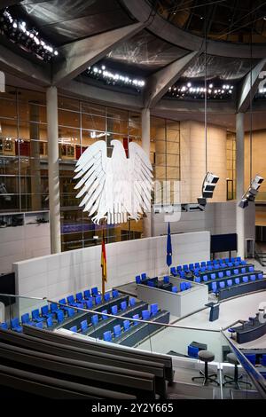 Innenansicht des Bundestagssaals in Berlin mit deutschem Adleremblem und leeren blauen Sitzen. Stockfoto