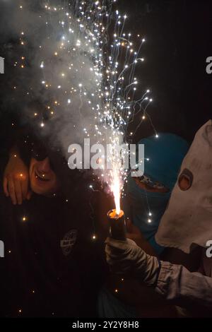 Korrefoc bei den San Juan Festlichkeiten in Jávea, Spanien, 24. Juni 2024. Nahaufnahme eines Teufels des Korrefoc, umarmt von jungen Männern mit Kapuze. Stockfoto