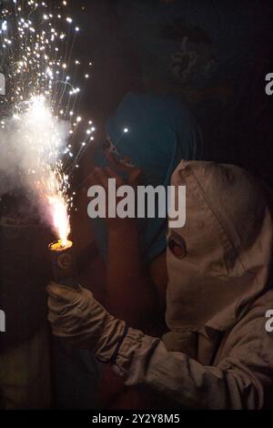 Korrefoc bei den San Juan Festlichkeiten in Jávea, Spanien, 24. Juni 2024. Nahaufnahme eines Teufels des Korrefoc, umarmt von jungen Männern mit Kapuze. Stockfoto