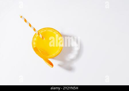 Orangensaft in einem Glas mit Strohhalm auf weißem Hintergrund für eine erfrischende Atmosphäre Stockfoto