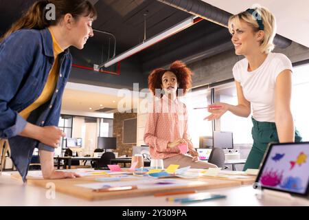 Brainstorming kreatives Schreibprojekt, drei multirassische Frauen arbeiten in modernen Büros zusammen Stockfoto