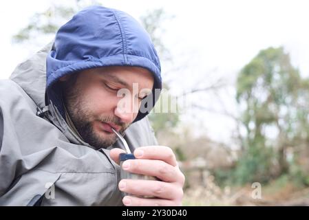 Junger argentinischer Mann trinkt Mate, ein traditionelles Heißgetränk, an einem kalten Wintermorgen. Sein Gesicht spiegelt das Gefühl des Wohlbefindens und des Wohlbefindens wider Stockfoto