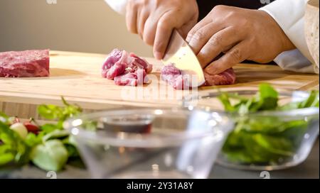 Der Metzger schwingt fachmännisch sein scharfes Messer, schneidet geschickt durch das rohe Fleisch, während die Muskeln unter seinen Ärmeln kräuseln, während er vorsichtig portioniert Stockfoto