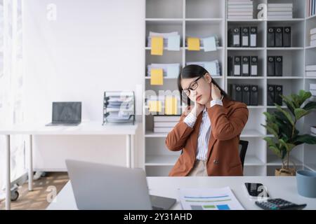 Geschäftsfrau plant eine Finanzprüfung, prüft Dokumente, während sie gegen das Burnout-Syndrom kämpft Stockfoto