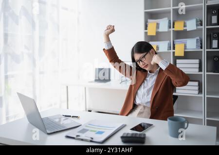 Geschäftsfrau plant eine Finanzprüfung, prüft Dokumente, während sie gegen das Burnout-Syndrom kämpft Stockfoto