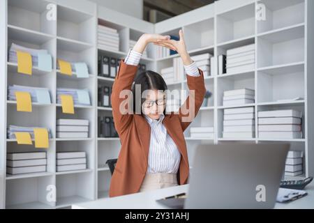 Geschäftsfrau plant eine Finanzprüfung, prüft Dokumente, während sie gegen das Burnout-Syndrom kämpft Stockfoto