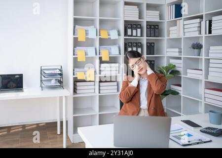 Geschäftsfrau plant eine Finanzprüfung, prüft Dokumente, während sie gegen das Burnout-Syndrom kämpft Stockfoto